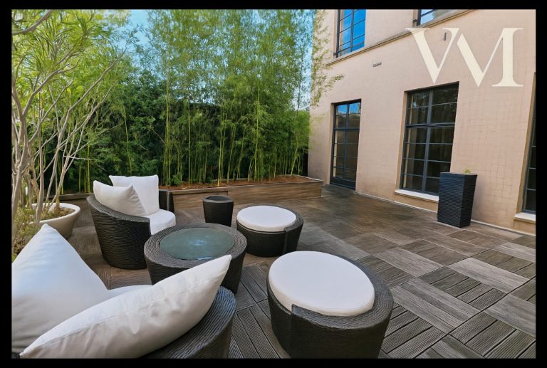 Terrasse privée de 44 m² Espace extérieur avec canapés et tables, entouré de verdure.